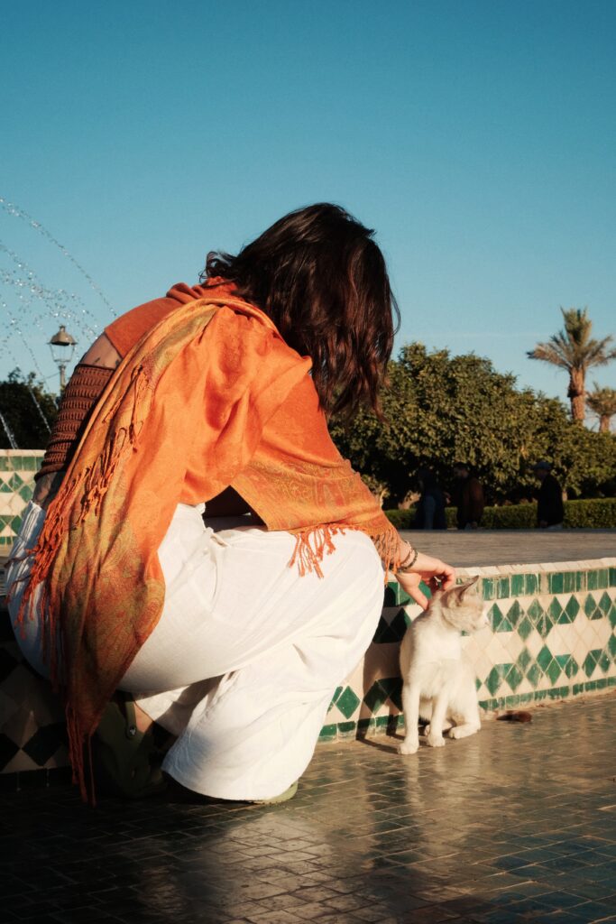 A woman in a bright orange scarf petting a kitten in Marrakech, shot on Fujifilm X-T2